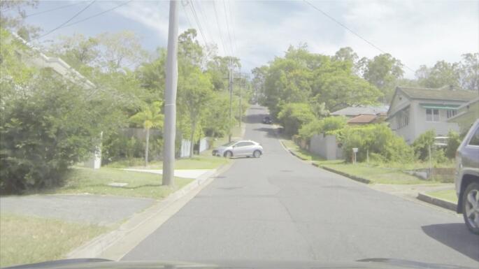 Still image from a video clip used in the Hazard Perception Test showing the road ahead from the driver’s perspective with a traffic conflict underway