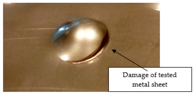 Tested metal sheet damage after the impact of 2 kg weight from 0.9 m height.
