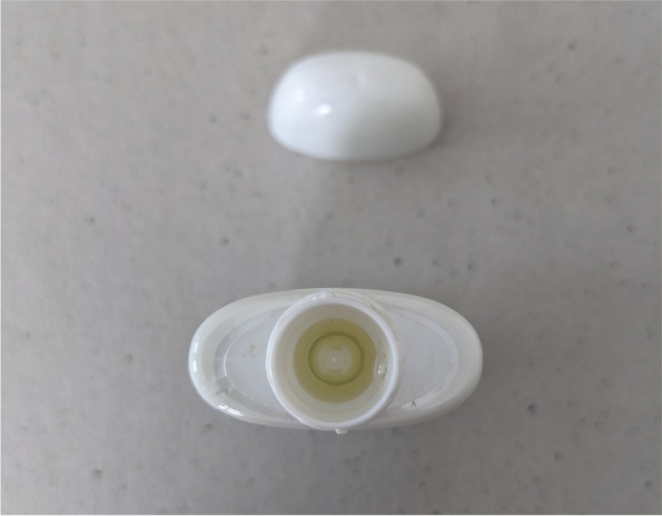 This image displays a top view of the select squeeze bottle with child-resistant safety cap removed. The dosage reservoir contained within the bottleneck of the device can be seen here as well as the overflow drain and conduit